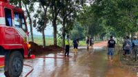 Polri Bersama Damkar dan Warga Bersihkan Tumpahan Tanah Urug yang Tercecer di Jalan